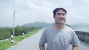 Yavaş hareket - Asya runner adam çalıştıran ve sokak, sağlıklı yakışıklı genç sportif erkek egzersiz yakın göl jogging. Yaşam tarzı uygun ve etkin erkekler sokak kavramı üzerinde egzersiz.