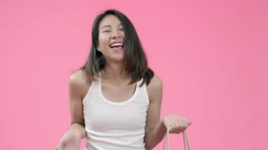 Genç güzel moda Asyalı kadın pembe arka plan stüdyo çekim üzerinde rahat giyim gülümseyerek mutlu duygu alışveriş torbaları tutan. Mutlu gülümseyen sevimli mutlu kadın başarı sevinir.