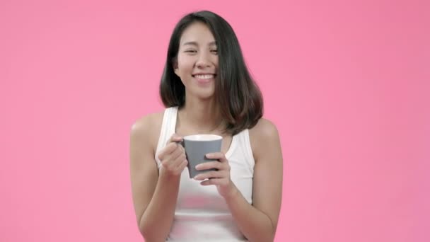 ピンクの背景スタジオショットの上にカジュアルな服でお茶のコーヒーを飲んで美しいアジアの女性を笑う 幸せな笑顔愛らしい喜んで女性は成功を喜ぶ — ストック動画