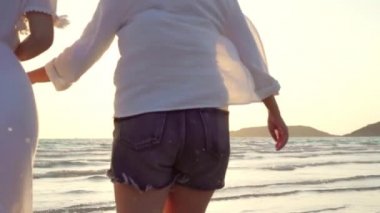 Yavaş çekim - Genç Asyalı lezbiyen çift sahilde çalışan. Güzel kadın arkadaşlar mutlu akşam gün batımında deniz kenarında plajda eğlenmek. Plaj konsepti lifestyle lezbiyen çift seyahat.