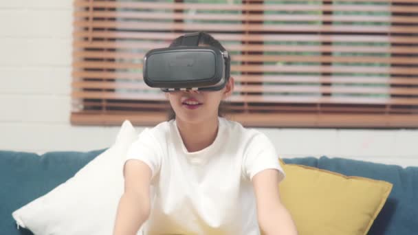 거실에서 비디오 게임을 안경을 사용하는 아시아 집에서 소파에 휴식을 취하는 — 비디오