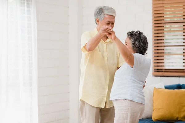 Asiatisches älteres Paar tanzt zusammen, während es zu Hause Musik im Wohnzimmer hört, süßes Paar genießt den Moment der Liebe, während es zu Hause entspannt Spaß hat. Lifestyle Senioren Familie entspannen zu Hause Konzept. — Stockfoto