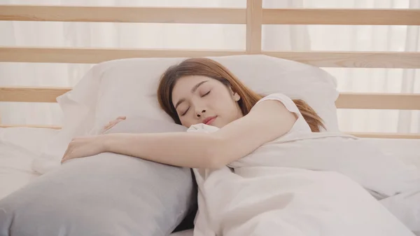 Aasialainen nainen haaveilee nukkuessaan sängyssä makuuhuoneessa, kaunis japanilainen nainen käyttää rentoutumisaikaa makaa sängyssä kotona. Elämäntapa naiset käyttävät rentoutumisaikaa kotona käsite . — kuvapankkivalokuva