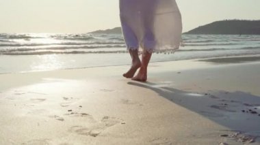 Yavaş çekim - Genç Asyalı kadın sahilde yürüyüş. Güzel kadın mutlu akşam gün batımı nda deniz kenarında sahilde yürüyüş rahatlayın. Yaşam tarzı kadın plaj konsepti seyahat.