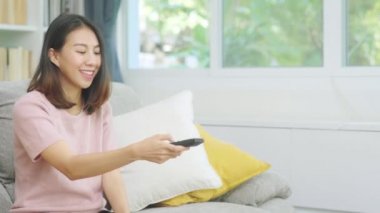 Genç Asyalı genç bir kadın evinde televizyon seyrediyor. Kadın oturma odasında kanepede uzanmış kendini mutlu hissediyor. Yaşam tarzı kadını sabah konseptinde rahatlar.. 
