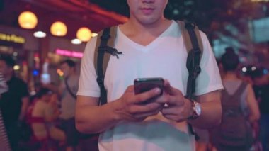 Gezgin Asya blogger erkekler Bangkok seyahat, Tayland, Khao San Road sosyal medya kontrol cep telefonu kullanarak erkek. Erkekler Tayland kavramı seyahat.