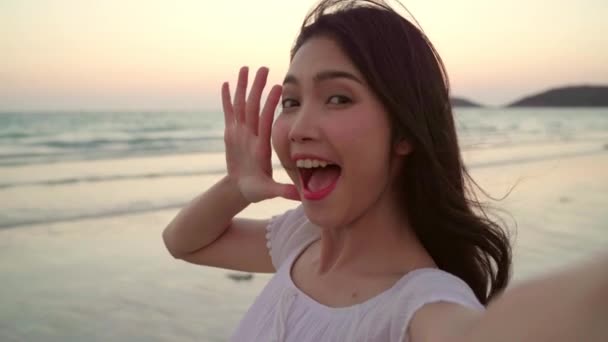 游客亚洲女人自拍在沙滩上 年轻美丽的女性快乐微笑使用手机自拍在海边的海滩当日落在晚上 生活方式 女性旅行海滩概念 — 图库视频影像