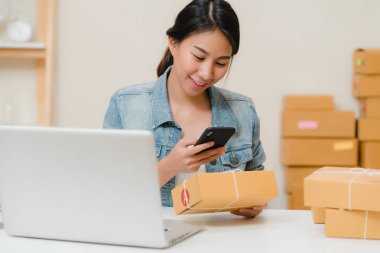 Güzel akıllı Asya genç girişimci iş kadın KOBİ ürün evde çalışan hisse senedi tarama qr kod üzerinde kontrol sahibi. Küçük işletme sahibi, ev ofis kavramı.