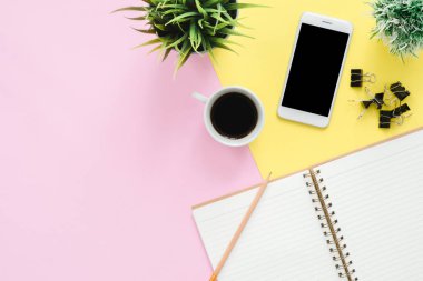 Ofis Masası adlı kullanıcının alanı - düz çalışma beyaz boş defter sayfası, kahve fincanı ve sahte telefon pastel arka plan üzerinde bir çalışma alanının en iyi görünümü yatırın. Pastel pembe sarı renk arka plan boşluk kavramı.