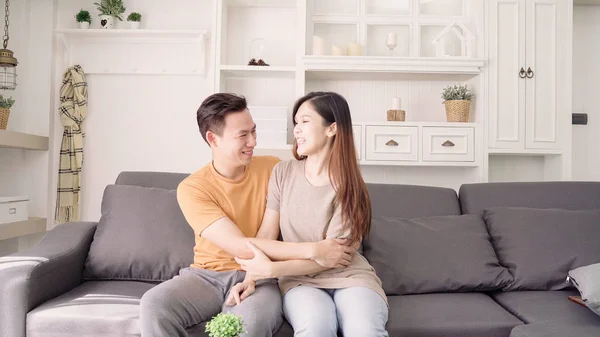 Asian couple hug together in living room at home, sweet couple enjoy love moment while lying on the sofa when relaxed at home. Lifestyle couple relax at home concept.