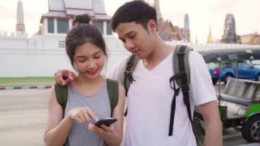 Yavaş hareket - Bangkok, Tayland, gün batımında tatil gezisi geçirirken harita görünümlü cep telefonu kullanarak tatlı çift yer haritası üzerinde Traveler Asya çift yön. Yaşam tarzı çift seyahat konsepti.