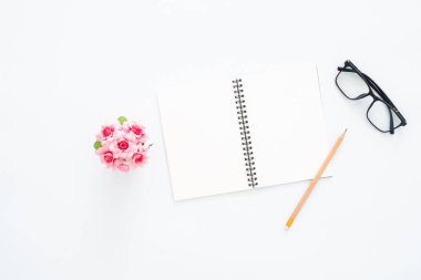 Yaratıcı düz fotoğraf çalışma masası yatıyordu. Üstten Görünüm Ofis Büro gözlük, kalem, boş defter ve beyaz renk arka plan üzerinde bitki ile. Kopya alanı, düz yatıyordu fotoğraf ile Üstten Görünüm.