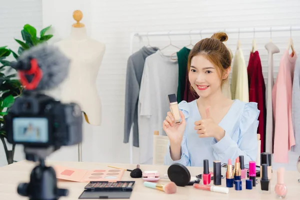 Skjønnhetsblogger presenterer skjønnhetskosmetikk foran kamera for opptak av video. Vakker asiatisk kvinne bruker kosmetikk mens anmeldelse utgjør en veiledende direktesending til sosialt nettverk via Internett . – stockfoto