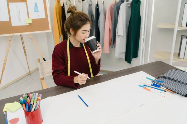 Magnifique créatrice de mode asiatique professionnelle qui travaille avec des croquis en tissu et dessine des vêtements au studio. Mode de vie femme concept de travail . — Photo