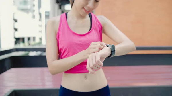 Zdrowe piękna młoda Azjatka sportowiec kobieta ustawienie i sprawdzanie postępu patrząc monitor pracy serca na inteligentny zegarek podczas pracy w miejskich miasta. Styl życia kobiet ćwiczenia w koncepcji miasta. — Zdjęcie stockowe