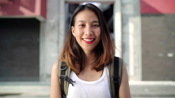 En munter, vakker ung asiatisk ryggsekkdame som er glad for å smile til kamera når hun reiser til Chinatown i Beijing, Kina. Livsstilsryggsekkturismebegrepet feriereise . – stockfoto