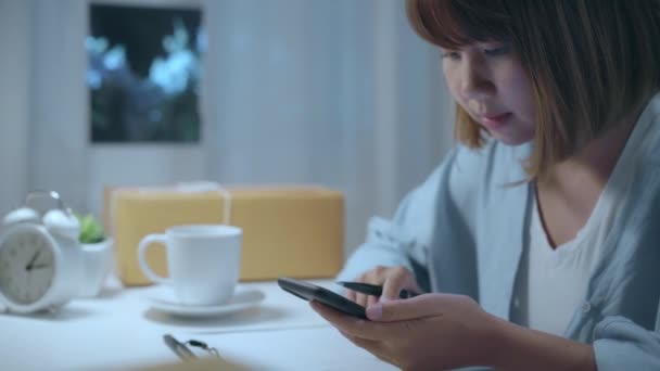 聪明的亚洲年轻企业家女老板Sme在线检查产品的股票和节省到手机工作深夜在家 小型企业所有者在家庭办公室的概念 — 图库视频影像