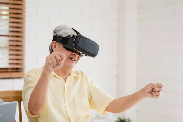 Asiatisches älteres Paar mit Tablet und Virtual-Reality-Simulator beim Spielen im Wohnzimmer, Paar, das sich glücklich fühlt, wenn es zu Hause auf dem Tisch liegt. Lifestyle Seniorenfamilie zu Hause Konzept. — Stockfoto