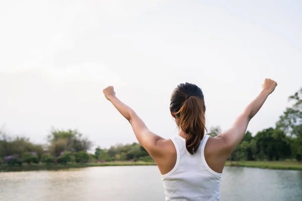 健康的年轻亚洲跑步者在温暖的光线下在公园的湖面附近锻炼和瑜伽前热身身体伸展。城市理念下的生活方式健身与积极的女性锻炼. — 图库照片