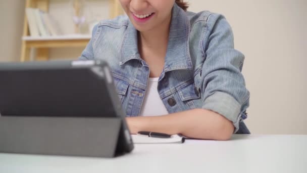 年轻的亚洲妇女使用平板电脑检查社交媒体 而放松在办公桌上在客厅在家里 享受在家的时间概念 — 图库视频影像