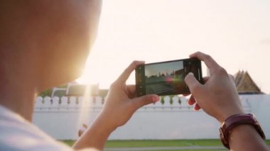 Bangkok tatil gezisi geçirirken bir fotoğraf çekmek için cep telefonu kullanarak Gezgin Asyalı adam, Tayland, erkek gün batımında inanılmaz dönüm noktasında yolculuk keyfini çıkarın. Yaşam tarzı erkekler şehir kavramı seyahat.