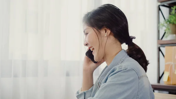 Kaunis älykäs aasialainen nuori yrittäjä liiketoiminnan nainen omistaja pk verkossa älypuhelimella vastaanottaa asiakkaalta ja käyttää kannettavaa tietokonetta työskentelee kotona. Pienyrityksen omistaja kotona toimisto käsite . — kuvapankkivalokuva