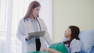 Güzel akıllı Asyalı doktor ve tartışmak ve Pano Doktor elinde bir şeyler olurken, hastanın yatakta Hastanesi'nde açıklayan hasta. Tıp ve sağlık kavramı.