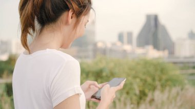 Akşam şehir şehir, sokakta yürürken smartphone dokunmatik ekran teknolojisi kullanan neşeli Asya Turizm blogger kadın. Yaşam tarzı sırt çantası turizm seyahat tatil kavramı.