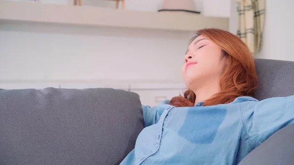 Wanita Asia yang tidur di sofa di ruang tamu, wanita Jepang yang cantik menggunakan waktu santai berbaring di tempat tidur di rumah. Wanita gaya hidup menggunakan waktu santai di rumah konsep . — Stok Foto