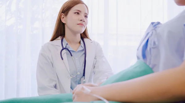 Jovem mulher médica asiática falando e segurando a mão para as mulheres paciente na cama doente. Medicina, idade, saúde, psiquiatra e conceito de pessoas . — Fotografia de Stock