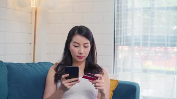 Молодая Улыбающаяся Азиатка Пользующаяся Смартфоном Покупает Покупки Кредитной Карте Лежа — стоковое видео