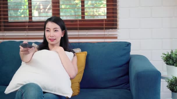 自宅でテレビを見ている若いアジアの女性は 女性の幸せリビングルームでソファの上に横たわる感じている ライフスタイルの女性は家のコンセプトで朝リラックス — ストック動画