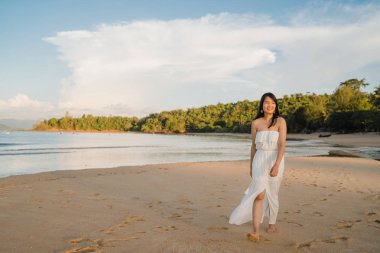 Sahilde yürüyen genç Asyalı kadın. Güzel kadın mutlu akşam gün batımı nda deniz kenarında sahilde yürüyüş rahatlayın. Yaşam tarzı kadın plaj konsepti seyahat.