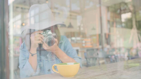 食物博主亚洲妇女使用相机拍照甜点, 面包和饮料, 而坐在咖啡馆的桌子上。生活方式美丽的女人放松在咖啡店的概念. — 图库照片