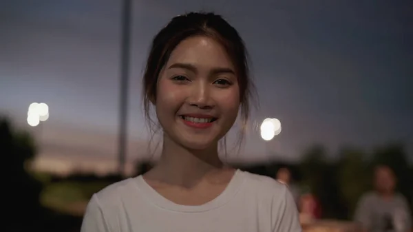 陽気な美しい若いアジアの女性は、夜のダウンタウンの街で通りを走行しながら、カメラに幸せな笑顔を感じて、陽気な美しい若いアジアの女性に幸せな笑顔を感じています。ライフスタイル観光旅行の休日のコンセプト。肖像画を見て — ストック写真