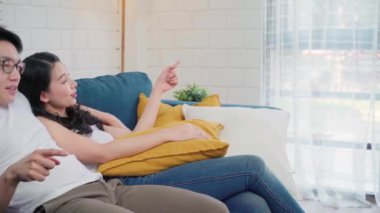 Asyalı çift evdeki oturma odasında birbirine sarılıyor, tatlı çift evde dinlenirken kanepede uzanırken aşk anının tadını çıkarıyor. Yaşam tarzı çifti ev kavramında rahatlar..