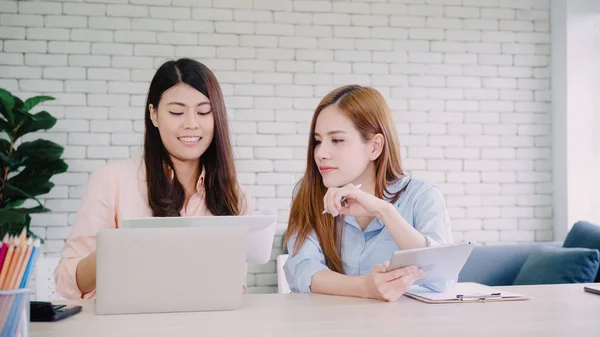 Asiatiske forretningskvinner i smart, tilfeldig antrekk som arbeider med bærbar datamaskin mens de sitter på skrivebord på kontorpult . – stockfoto