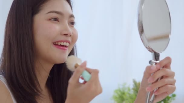 ブラシでパウダーを使用するアジアの女性は フロントミラーでメイクアップ 自宅で寝室で働く準備ができて自分自身を改善するために美容化粧品を使用して幸せな女性 家庭のライフスタイル女性のコンセプト スローモーションショット — ストック動画