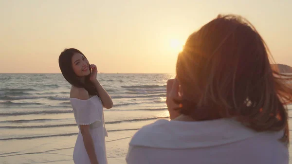 Junges asiatisches lesbisches Paar, das sich in Strandnähe gegenseitig fotografiert. schöne Frauen lgbt Paar glücklich romantischen Moment, wenn Sonnenuntergang am Abend. Lifestyle lesbisches Paar reist am Strand Konzept. — Stockfoto