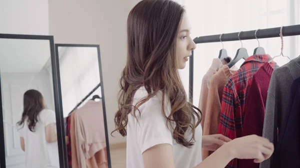 Armoire à domicile ou vestiaire de magasin de vêtements. Asiatique jeune femme choisissant ses vêtements de tenue de mode dans le placard à la maison ou magasin. Fille pense quoi porter pull . — Photo