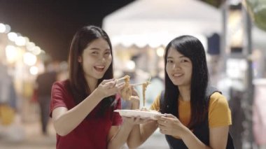 Asyalı genç kadın arkadaşlar Bangkok seyahat, Tayland, güzel kadın mutlu yürüyüş hissi ve Khao San Road Pad Tay yeme. Kadınlar seyahat sokak gıda kavramı yemek. Yavaş çekim çekimi.