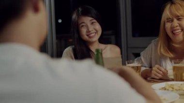 Bira kızartma ve evde kutlayan içecek şişeleri ile gülerek ve genç Asyalı arkadaşlar grubu. Mutlu genç arkadaşlar yaz gecesi parti kutlama müzik dinlerken.