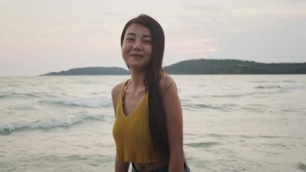 年轻的亚洲女人在沙滩上感到快乐 美丽的女性快乐放松微笑的乐趣在海边的海滩当日落在晚上 生活方式女孩旅游假期暑假概念 慢动作拍摄 — 图库视频影像