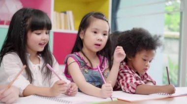 Yavaş hareket - Sınıf çizim çocuk grubu, Çok ırklı genç erkek ve kız mutlu komik çalışma ve ilkokulda kağıt üzerinde boyama oynamak. Okul konseptinde çocuk çizimi ve boyama.