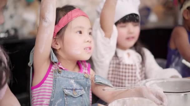 教室で一緒にケーキを焼く子供たちのグループ 多民族の若い男の子と女の子は学校の台所でデザート料理を作って幸せ 学校のコンセプトで調理する子供たち — ストック動画