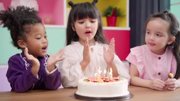 子供たちのグループは 教室で誕生日のパーティーを祝う 多民族の若い男の子と女の子は幸せな学校でバースデーケーキにキャンドルを吹き消す願いを作ります 子供たちは学校のコンセプトで誕生日を祝う — ストック動画