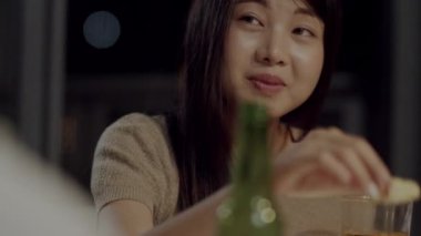 Bira kızartma ve evde kutlayan içecek şişeleri ile gülerek ve genç Asyalı arkadaşlar grubu. Mutlu genç arkadaşlar yaz gecesi parti kutlamamüzik dinlerken. Yavaş çekim çekimi.