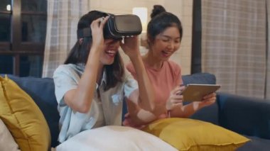 Lezbiyen lgbt kadın çift evde tablet kullanarak, Asyalı kadın gece oturma odasında kanepe yatarken birlikte oyun oynarken dizüstü bilgisayar ve Vr kullanarak mutlu hissediyorum. Lover tatil konsepti kutlamak.