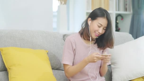 Azjatka Słuchająca Muzyki Korzystająca Smartfona Kobieta Korzystająca Relaksu Leżąca Domowej — Wideo stockowe