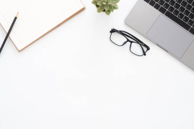 Yaratıcı düz Fotoğraf çalışma masası yatıyordu. Üstten görünüm ofis büro dizüstü bilgisayar, Gözlük, kalem, defter ve beyaz renk arka plan üzerinde bitki. Kopya alanı, düz yatıyordu fotoğraf ile üstten görünüm.